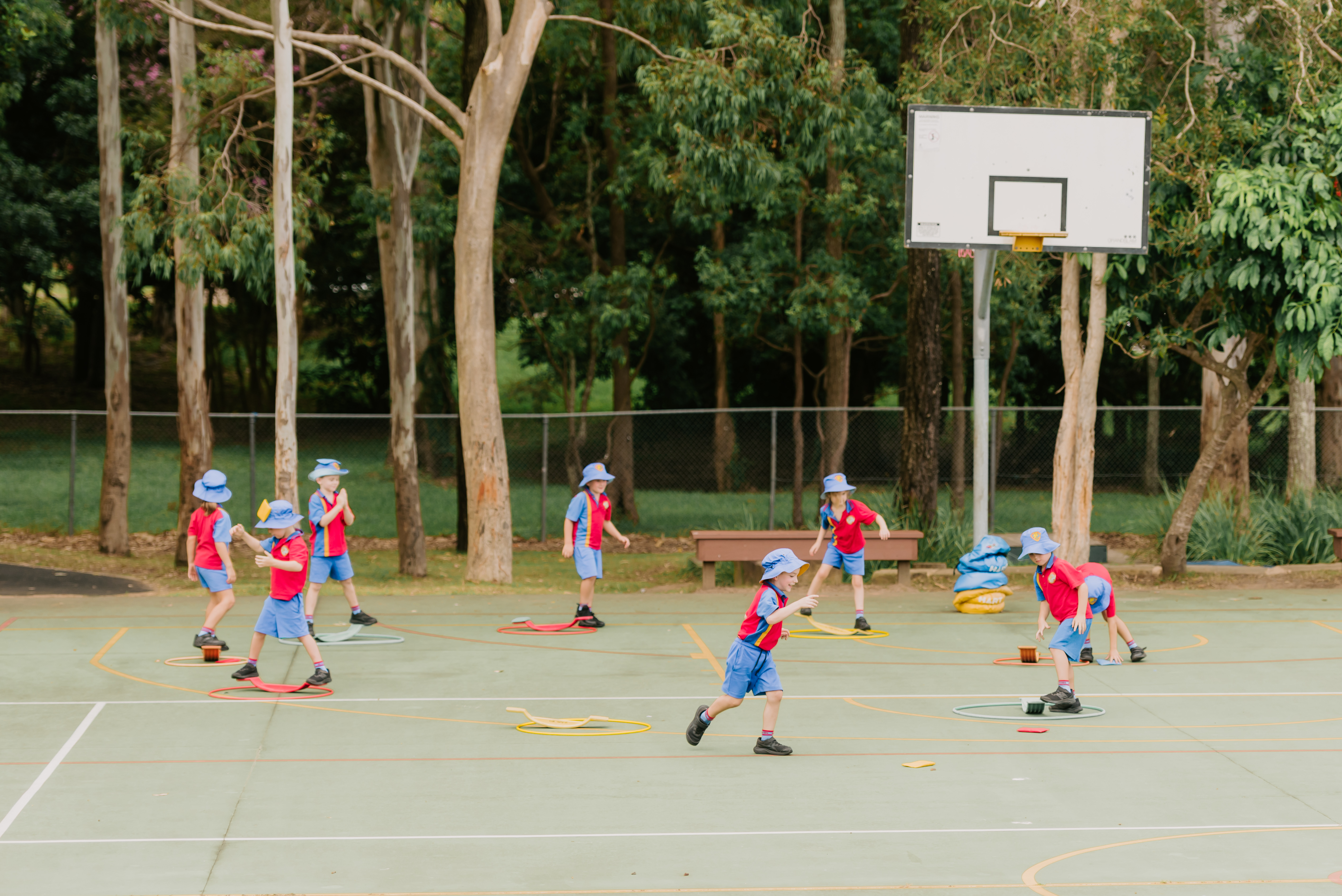Students taking part in an outdoor physical activity using hoops and balance equipment.