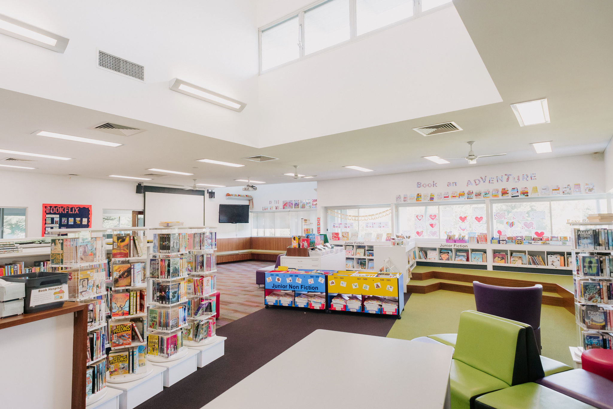 Five students in school uniform sitting together and reading a book in a school library.