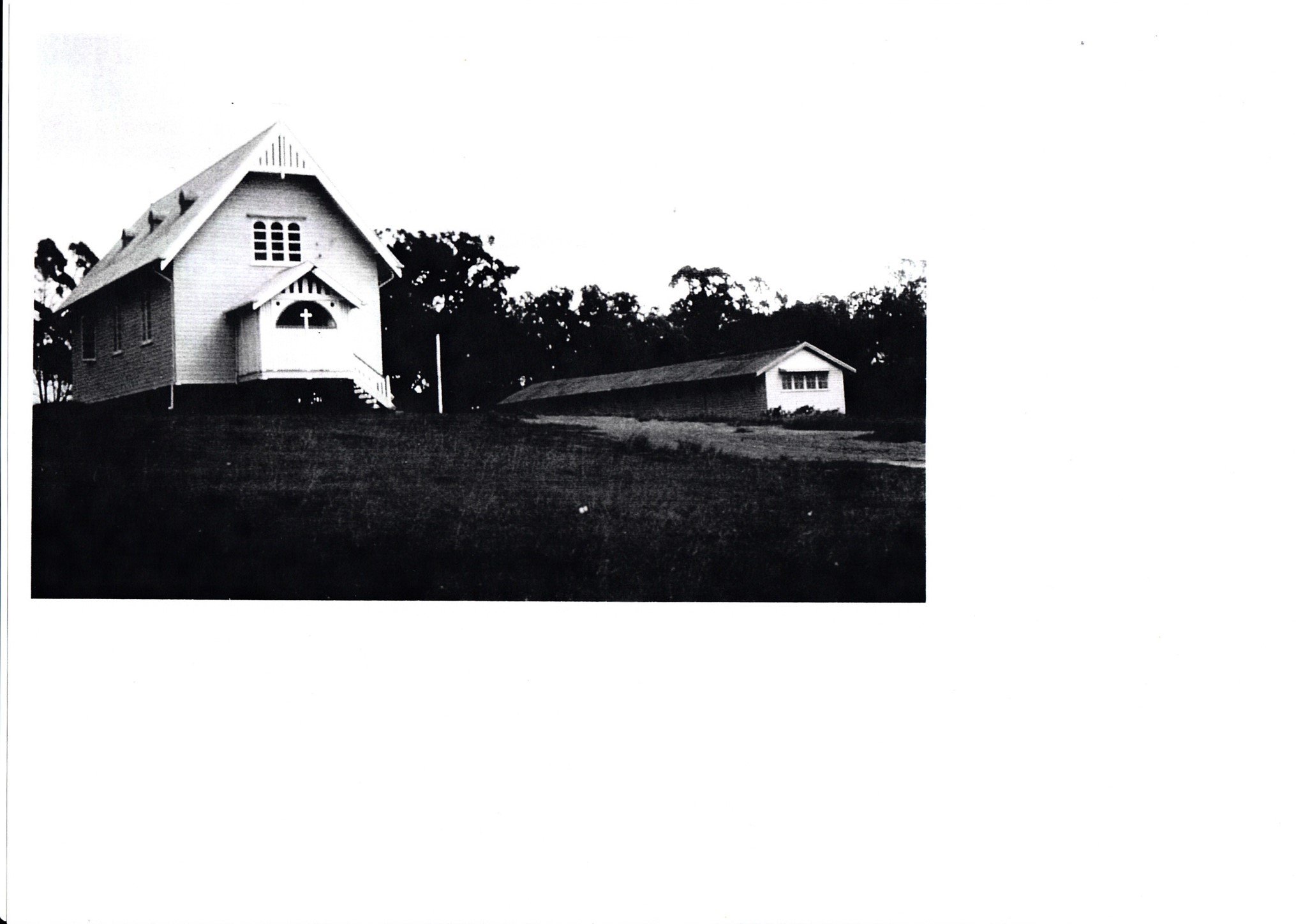 Archival photograph of an early timber church and nearby building.